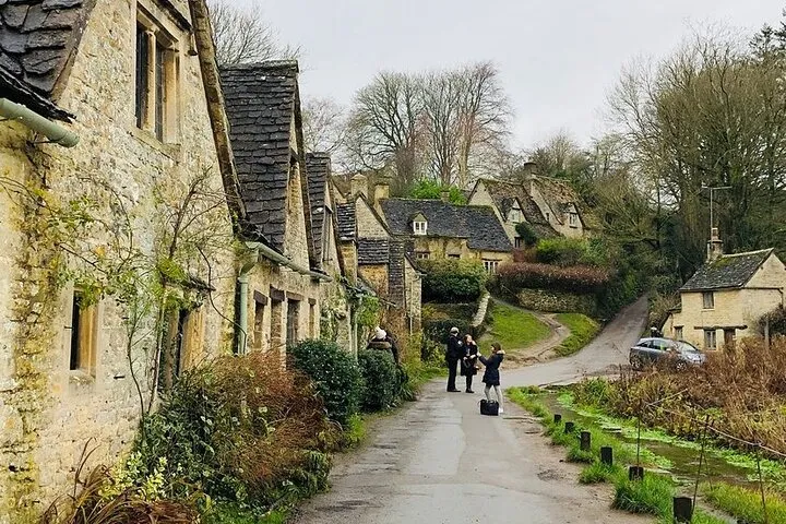 Honey-stone cottages along a stream in a Cotswolds village on a small-group day tour from London, England