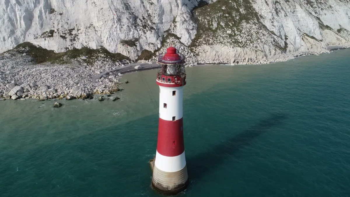 Red and white Beachy Head Lighthouse below the chalk cliffs on a Seven Sisters day trip from London