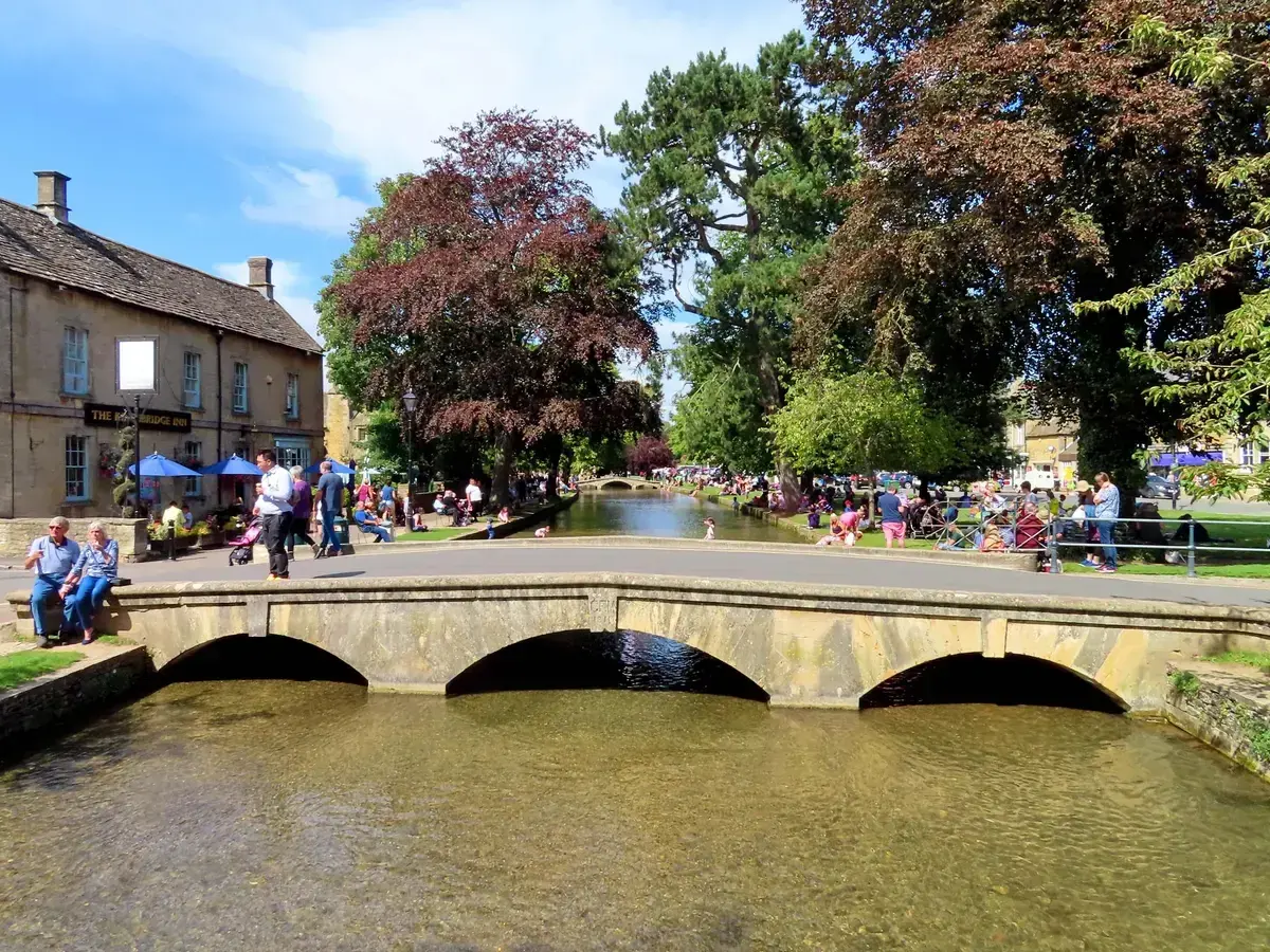 Stone footbridge over the River Windrush in Bourton-on-the-Water on an Oxford and Cotswolds day trip from London